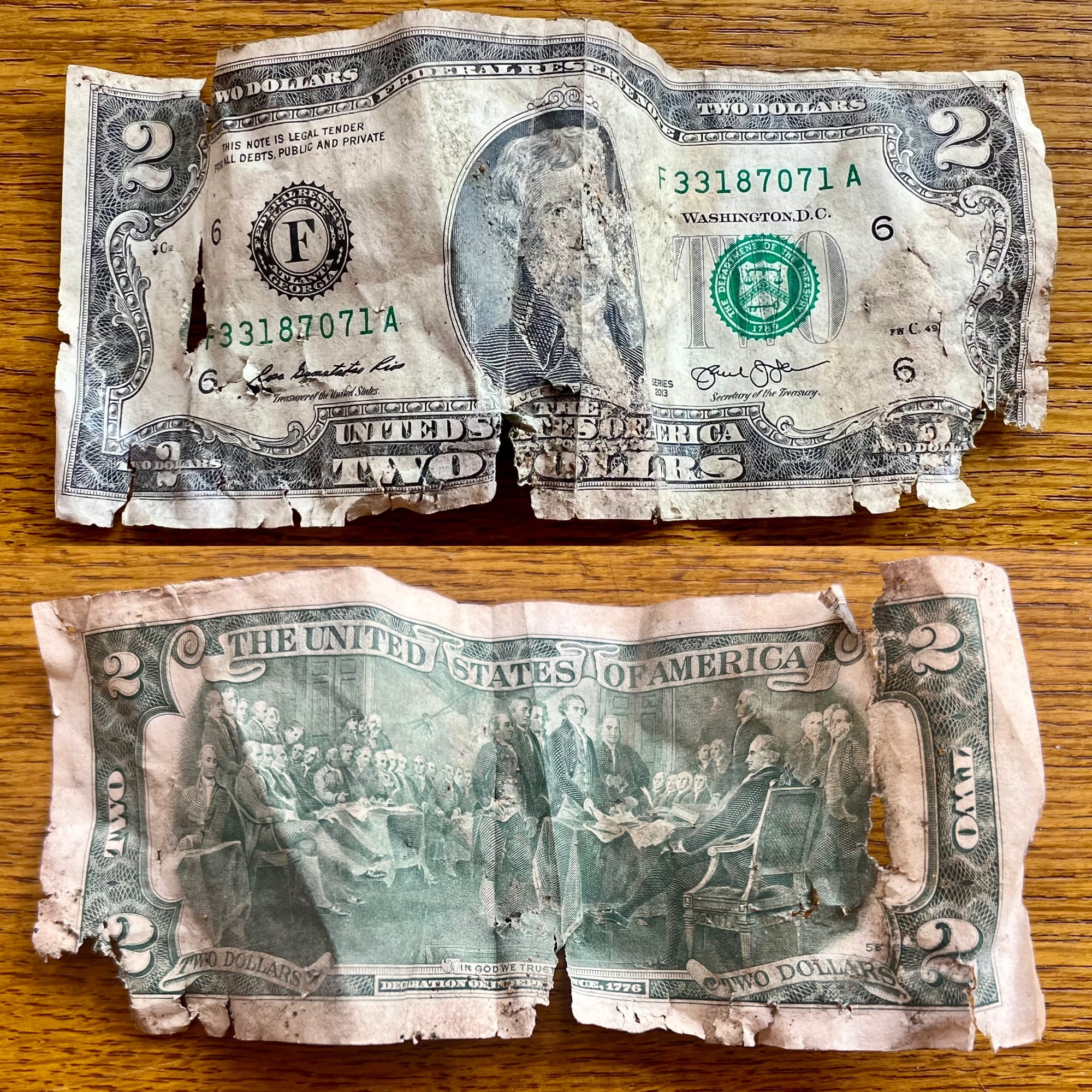 Both sides of a ratty two-dollar bill.