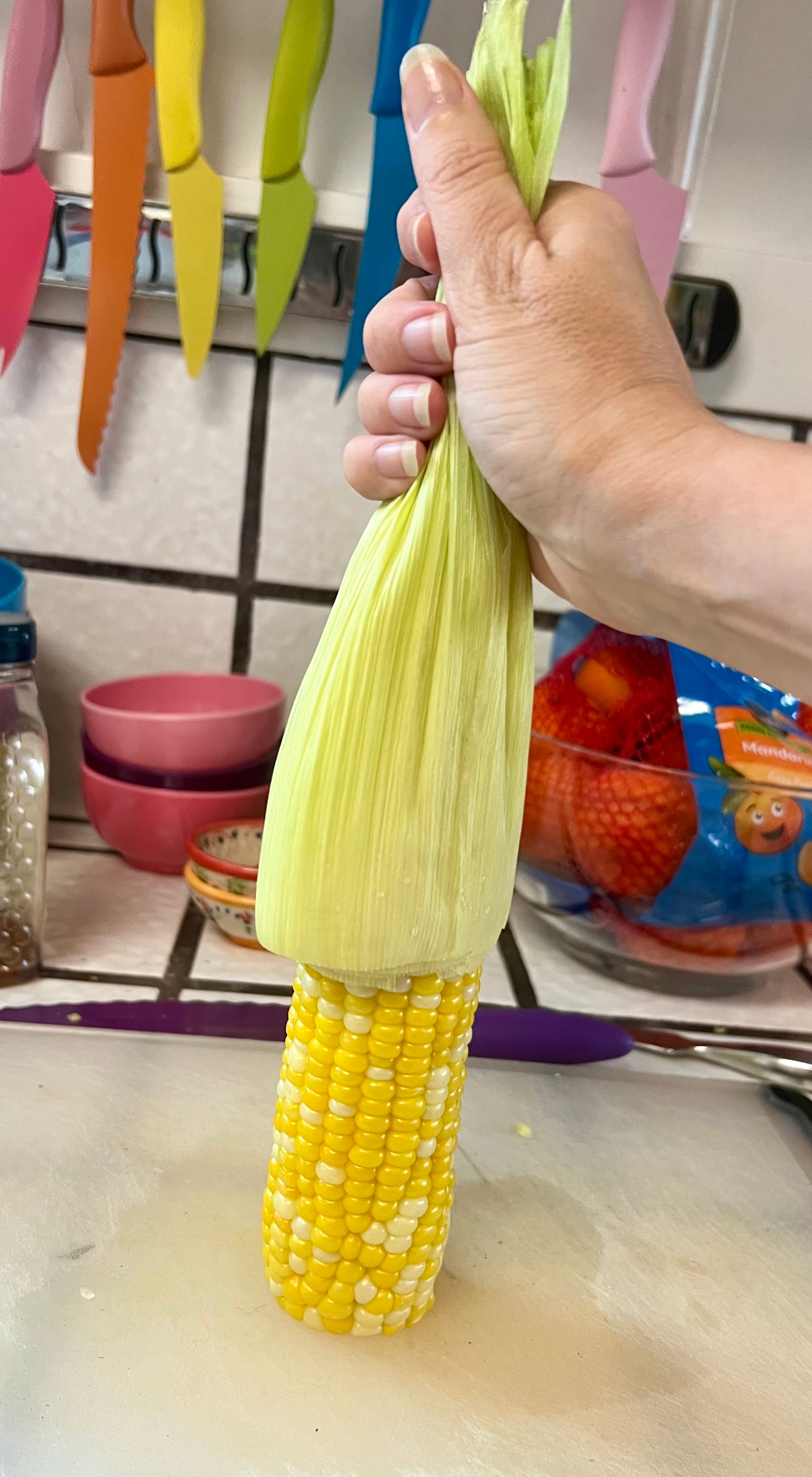Grip the cornhusk at the top of the ear, and shimmy-shake the ear, encouraging it to slip downward.